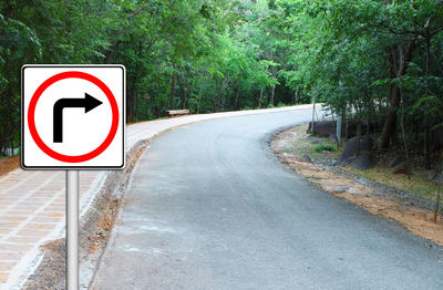 Road sign by trees in city