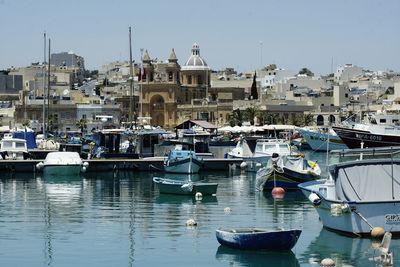 Boats moored at harbor against sky