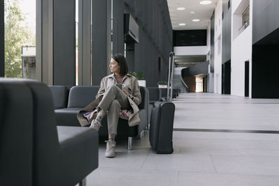 Woman with suitcase sitting in lobby