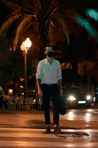 Full length of man standing on illuminated street at night