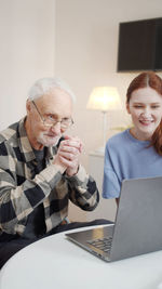 Smiling senior man and nurse looking at laptop