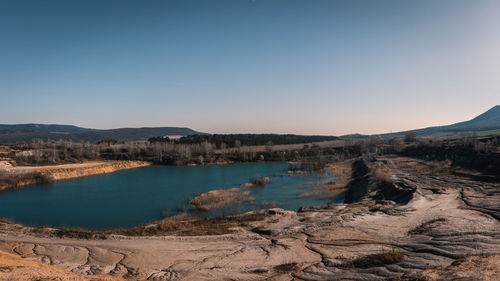 Scenic view of lake and mountains against clear blue sky