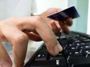 Close-up of person using computer while holding credit card