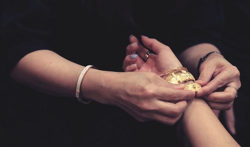 Saleswoman wearing bangles to woman at store