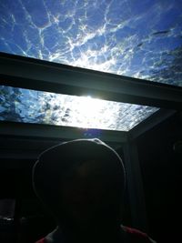 Low angle portrait of silhouette man against sky seen through window