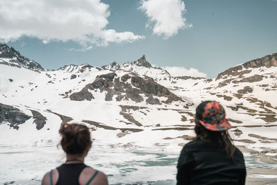 Rear view of woman on snowcapped mountain against sky