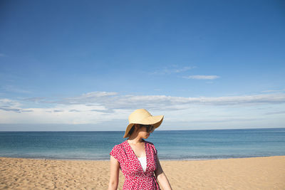 Rear view of senior woman on beach against sky