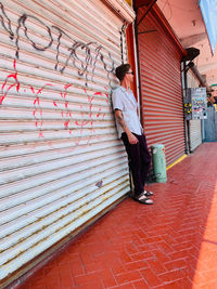 Man standing on footpath by building