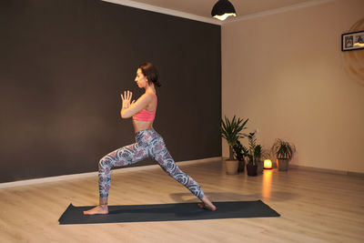 Young woman doing yoga on yoga mat in atmospheric yoga studio