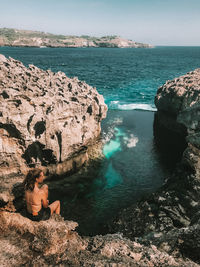 Woman sitting on rock by sea