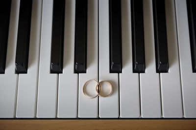 High angle view of wedding rings on piano keys