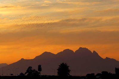 Scenic view of silhouette mountains against romantic sky at sunset