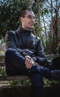 Young man looking away while sitting on land