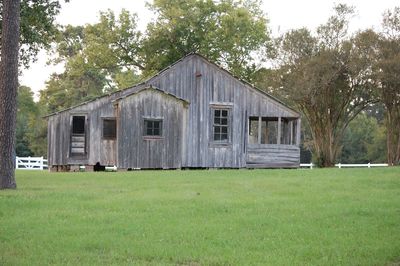 Old house on field against trees