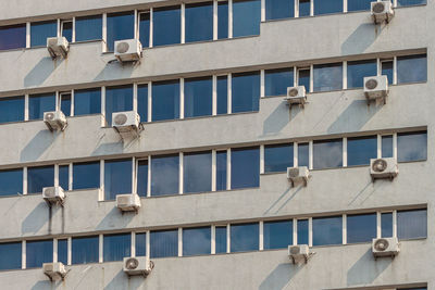 Lots of air conditioners on the wall of the building