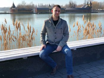 Portrait of man sitting by lake in city