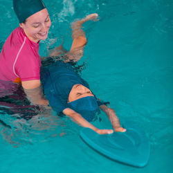 Boy learning to swim in pool with teacher