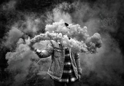 Man standing amidst smoke outdoors