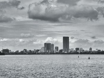 Sea by city buildings against sky