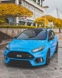 Blue car on street against buildings