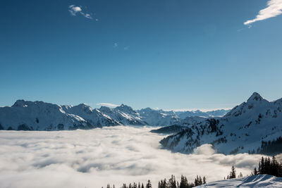 Scenic view of snowcapped mountains against blue sky