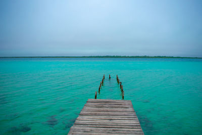 Pier over sea against blue sky