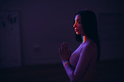 Side view of woman looking away against black background