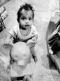 High angle view portrait of cute girl sitting on toy at home