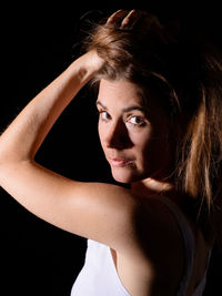 Close-up portrait of beautiful young woman against black background