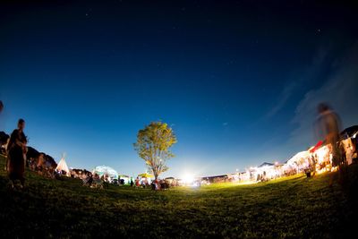 People at music concert on field against sky during night