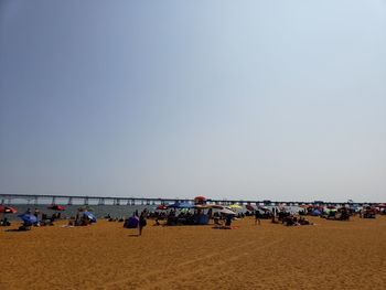 People on beach against clear sky