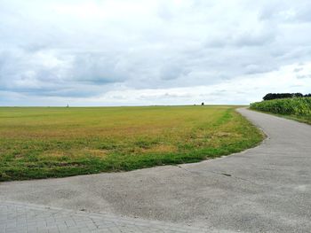 Road amidst field against sky