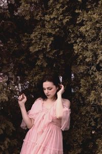 Woman standing against pink and trees