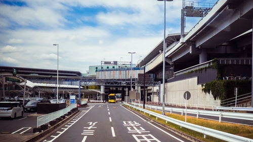 Vehicles on road against sky in city