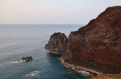 Rock formations by sea against sky