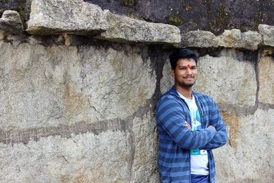 Portrait of young man standing against wall