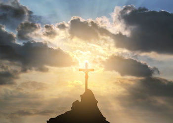 Jesus  cross of silhouette statue against sky at sunset