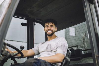 Portrait of happy young construction worker sitting in vehicle