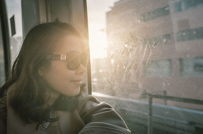 Side view of woman looking through window in train