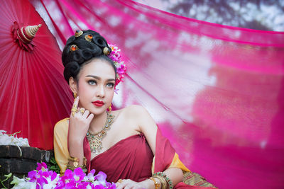 Young woman sitting by pink fabric