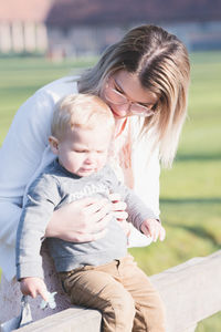 Side view of mother and daughter sitting on field