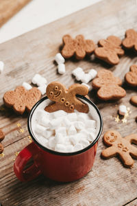 Ginger man in a cup of cocoa with a big red bow on a wooden background, top view.