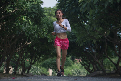 Portrait of smiling young woman against trees