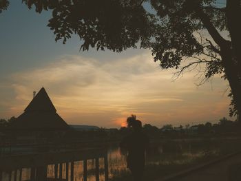 Silhouette of woman standing against sky during sunset