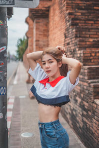 Full length of woman standing against brick wall