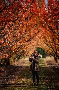 Full length of woman standing by tree during autumn