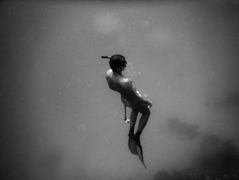 Side view of man jumping against sky