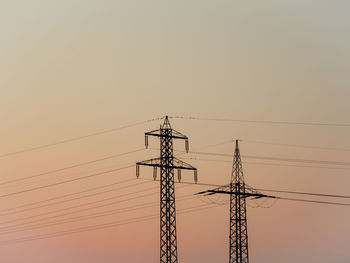 Low angle view of silhouette electricity pylon against romantic sky