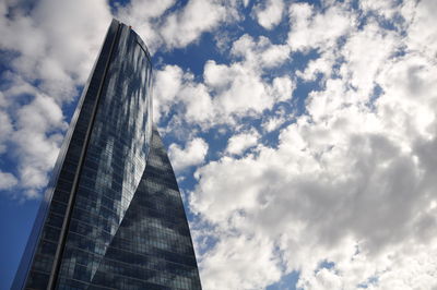 Low angle view of skyscrapers against cloudy sky