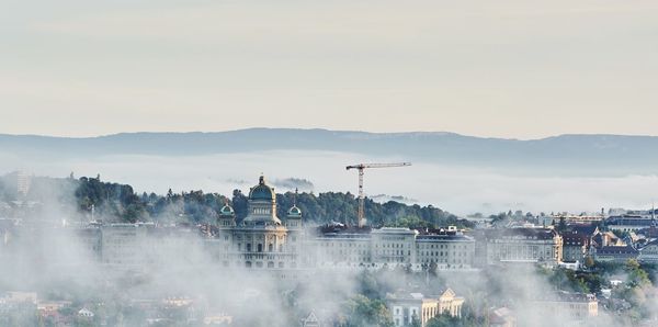 Buildings in city during foggy weather against sky